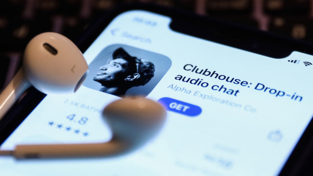 a phone screen showing the clubhouse app with a pair of airpods on top