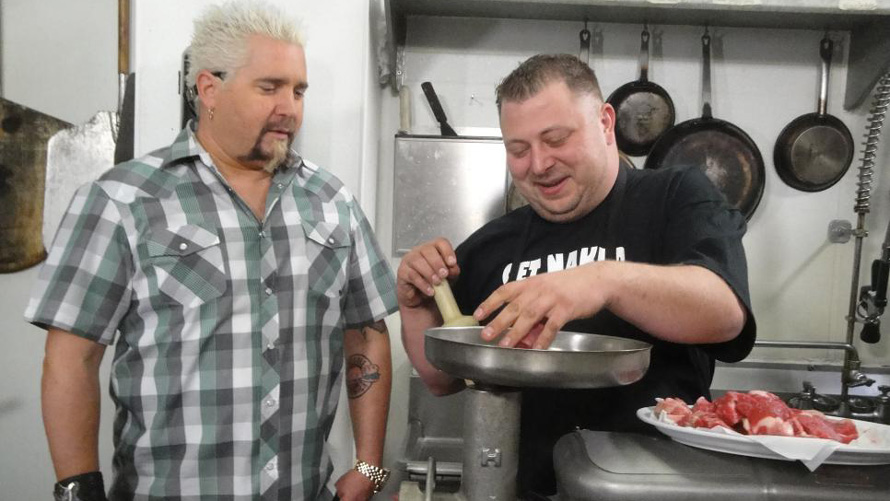 guy fieri standing next to a chef in a kitchen