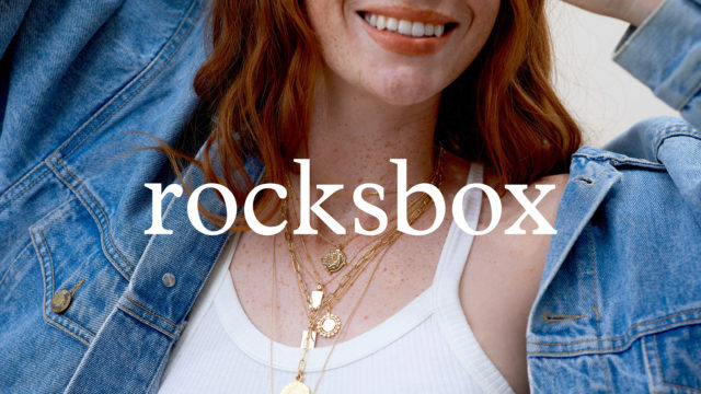a freckly red head from the mouth down, showing a bunch of gold necklaces around her neck
