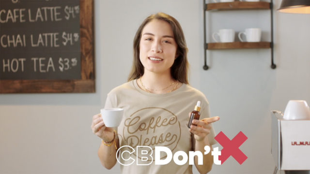 A woman in a coffee shop holds a CBD dropper and a coffee cup with C B Don't written on the screen