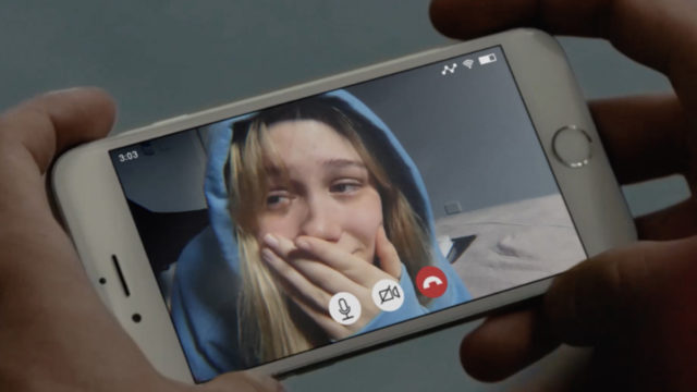A teen girl in a hoodie looks distraught in the screen of a video call