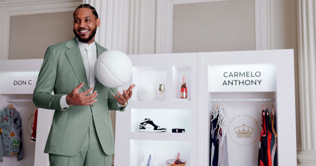Suited Carmelo Anthony standing next to a display case
