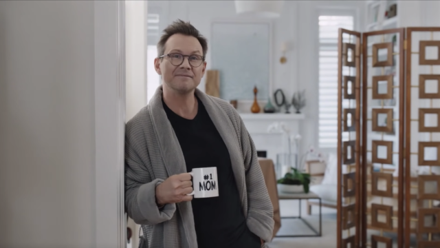 Christian Slater in a robe holding a mug that says 