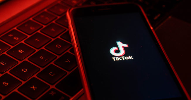 Photo of cell phone loading TikTok app in red light,