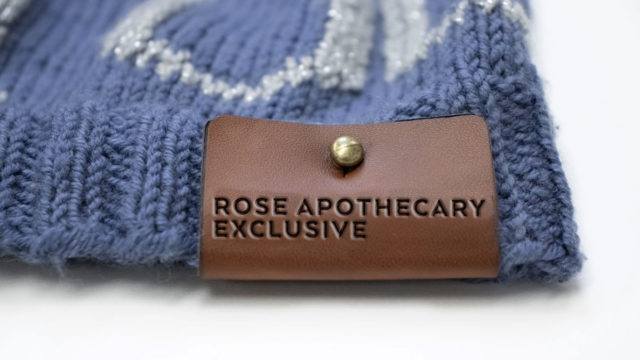 A purple knitted garment is shown with the leather label saying Rose Apothecary Exclusive