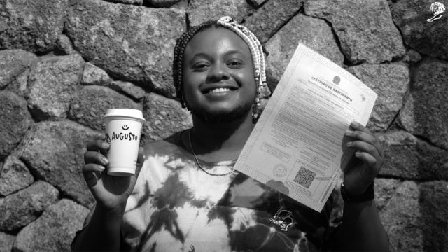 A trans person holding their Starbucks coffee and name-changing documents