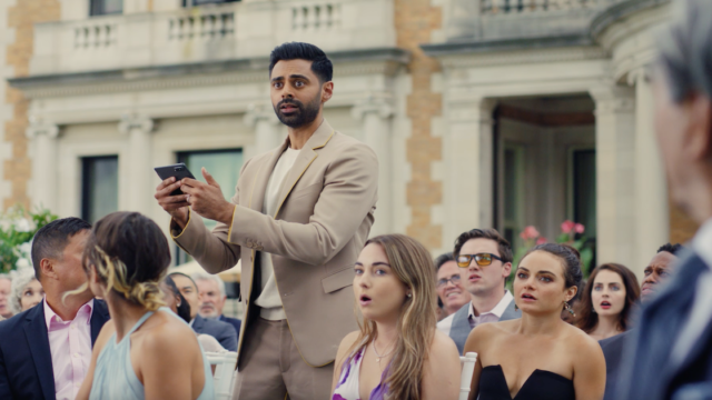 Hasan Minhaj standing in the middle of a seated crowd