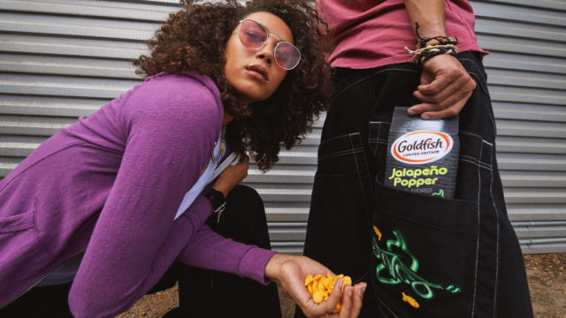 A woman posing next to a person holding Goldfish Crackers in JNCO jeans