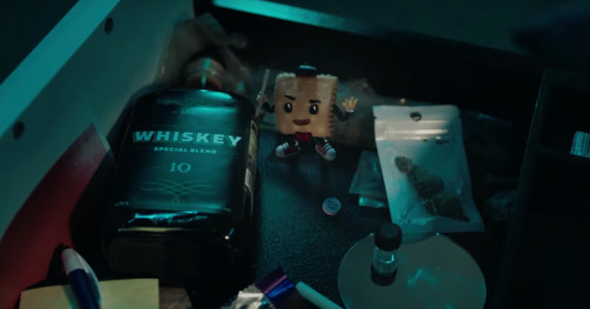 A cartoon cracker standing between whisky and drugs