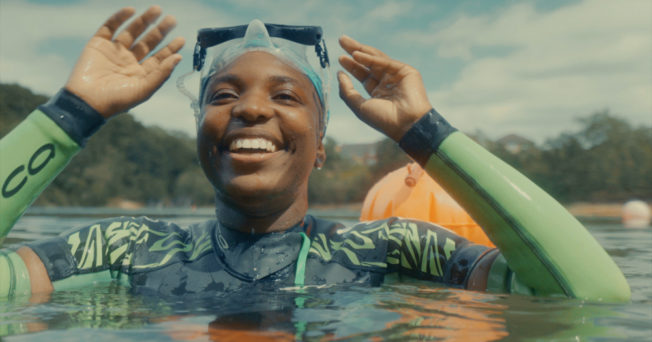 Woman in swimming cap smiling in the water
