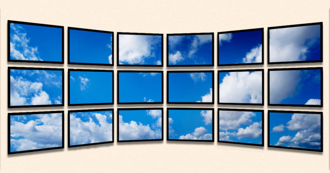 Various tv screens on a wall displaying blue skies.