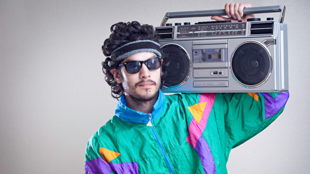 Photo of a man in retro outfit holding a boombox.