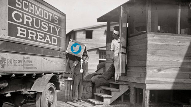 A black and white photo of Schmidt Baking Company trucks with a worker carrying a crate with the Twitter logo photoshopped onto it
